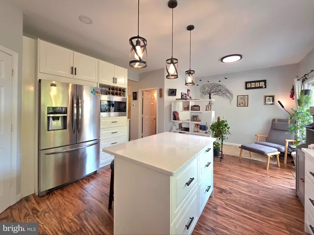 a kitchen with stainless steel appliances granite countertop a refrigerator a sink dishwasher a stove and white cabinets with wooden floor