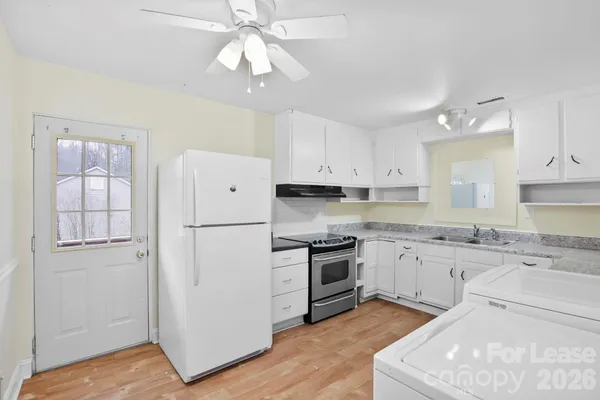 a kitchen with granite countertop white cabinets and white appliances
