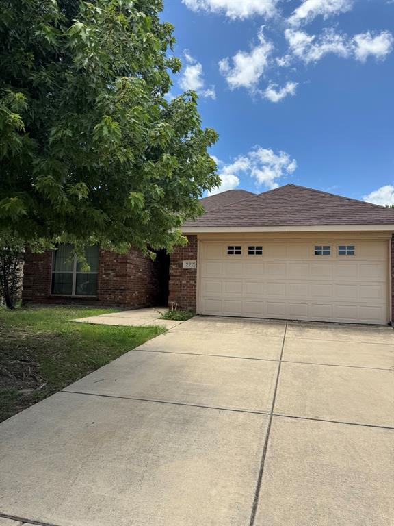 222 Range Road Waxahachie, TX 75165 - Photo 1 of 1 Brick facade residence featuring a two-car garage with panel detailing, a concrete driveway, and mature landscaping
