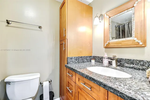 a bathroom with a granite countertop sink toilet and shower