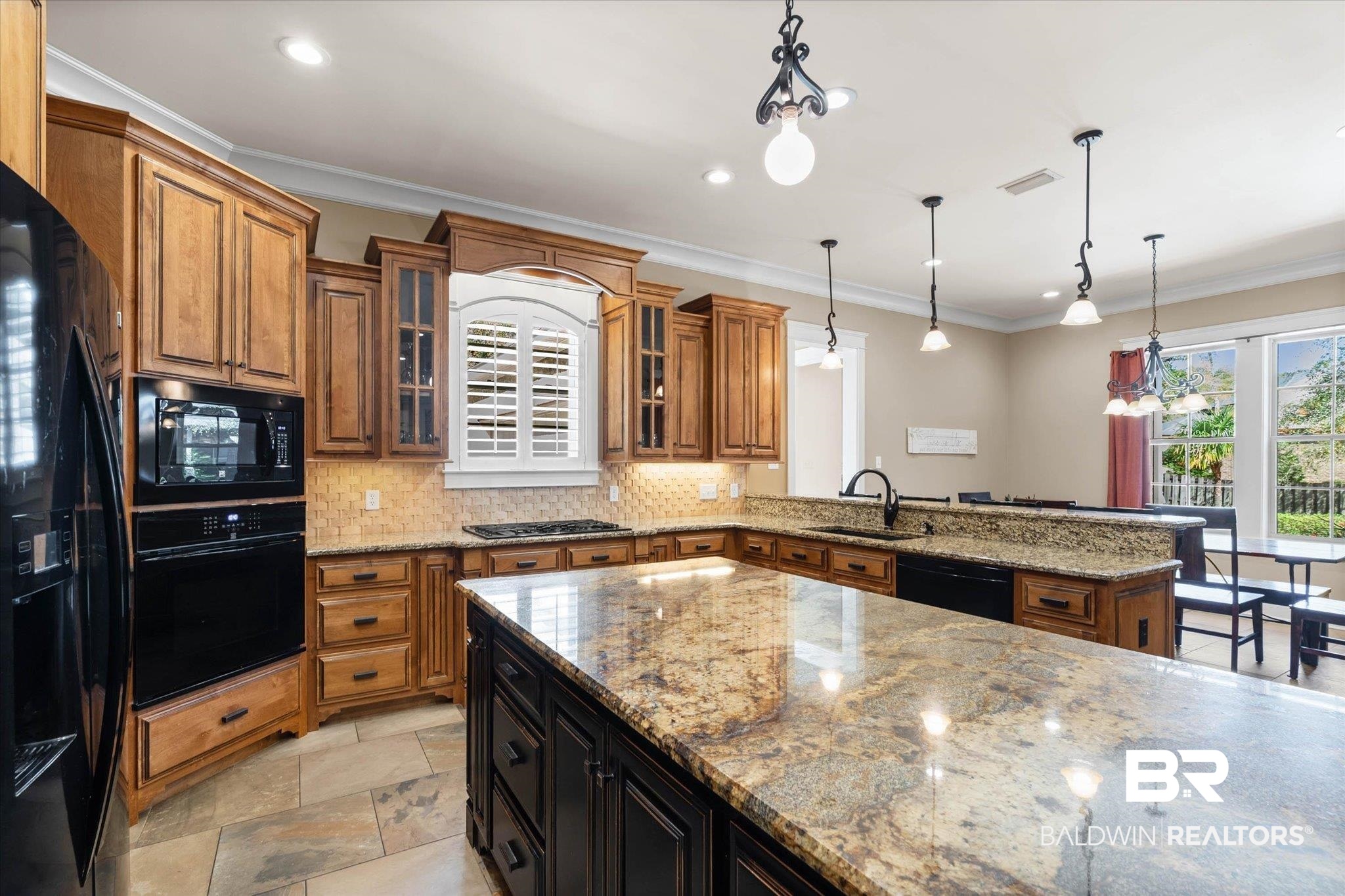 7676 Rockstone Lane Mobile, AL 36695 - Photo 12 of 47 Kitchen with light stone countertops, tasteful backsplash, black appliances, glass insert cabinets, and crown molding