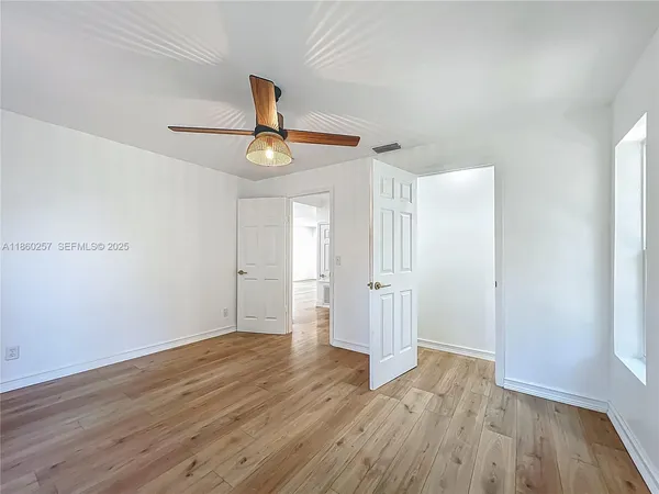 a view of empty room with wooden floor and fan