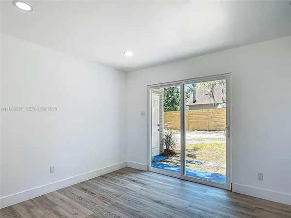 a view of a hallway with wooden floor and a bathroom