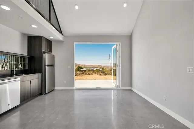 a view of an empty room with a window and kitchen view