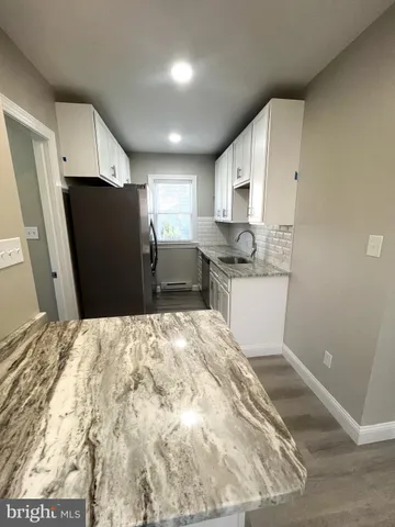 a kitchen with granite countertop a refrigerator and a sink
