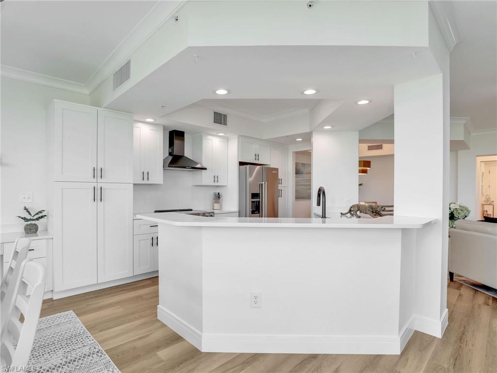 325 Dunes Boulevard, Unit 403 Naples, FL 34110 - Photo 11 of 49 a kitchen with stainless steel appliances a sink a stove a refrigerator cabinets and a dining table