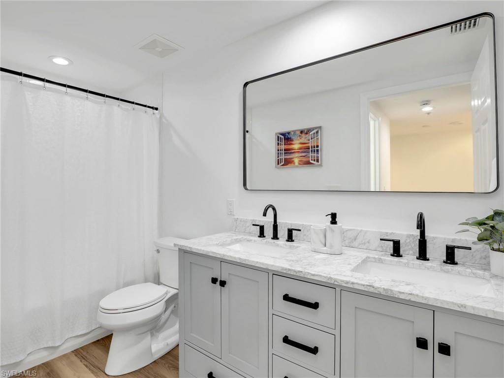 325 Dunes Boulevard, Unit 403 Naples, FL 34110 - Photo 31 of 49 a bathroom with a toilet a sink and mirror