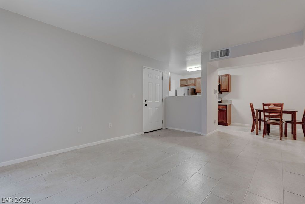 7885 West Flamingo Road, Unit 1016 Las Vegas, NV 89147 - Photo 4 of 24 A spacious living area with ceramic tile flooring leads into a functional kitchen and dining space.
