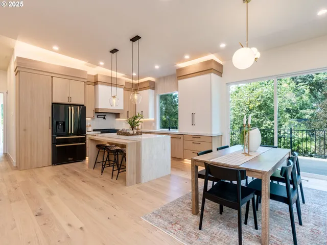 a kitchen with kitchen island a dining table chairs stainless steel appliances and cabinets