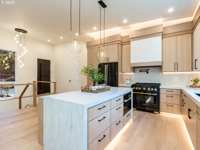 a kitchen with stainless steel appliances kitchen island granite countertop a stove a sink and a refrigerator