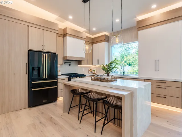 a kitchen with stainless steel appliances a stove a refrigerator a sink and a refrigerator with wooden floor