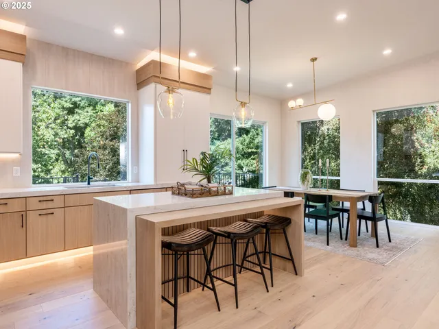 a kitchen with kitchen island a large window and chairs