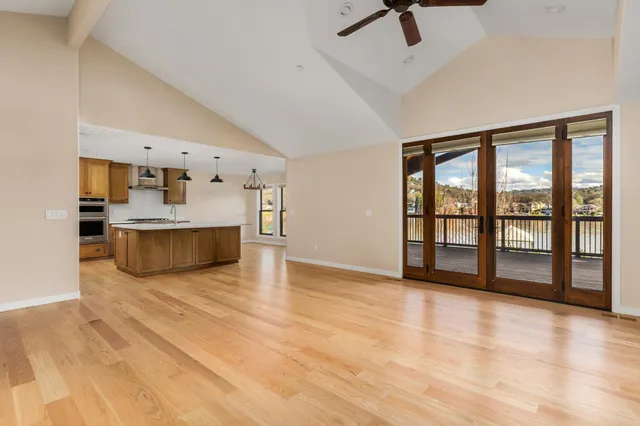 a view of an empty room with a window and kitchen view