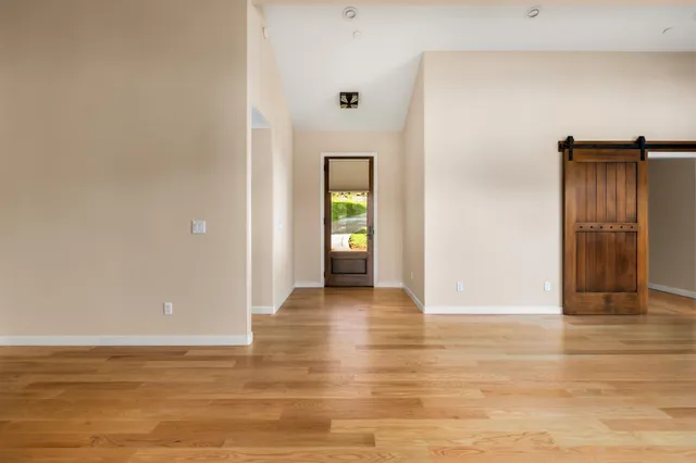 a view of an empty room with window and wooden floor