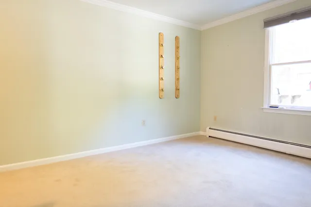 a view of an empty room with a window and a kitchen