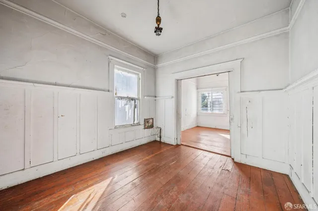 a view of empty room with wooden floor and fan