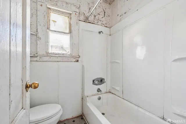 a bathroom with a bathtub toilet and window