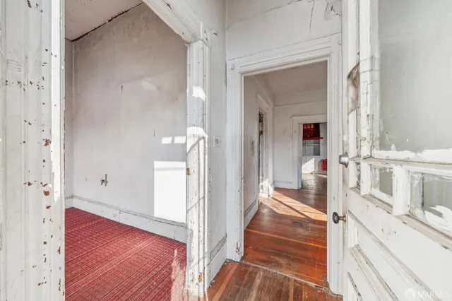 a view of a hallway with wooden floor and a living room