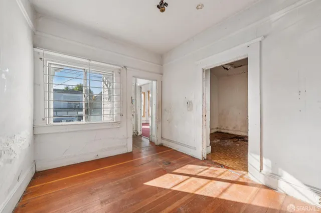 a view of an empty room with window and wooden floor