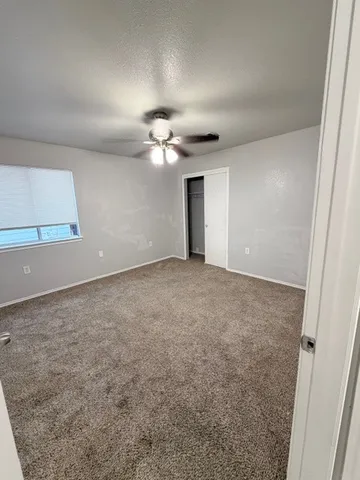 an empty room with a ceiling fan and a window