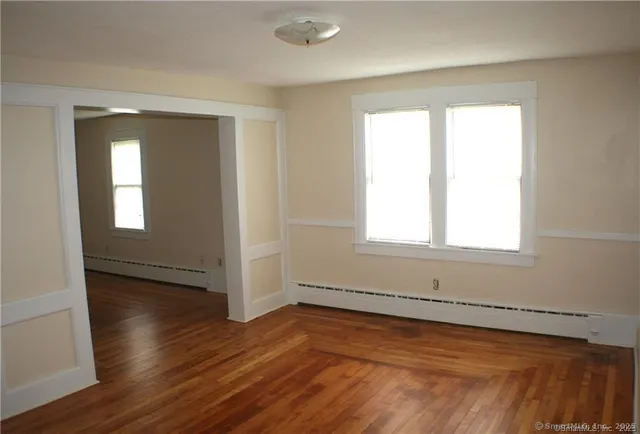 a view of an empty room with wooden floor and a window