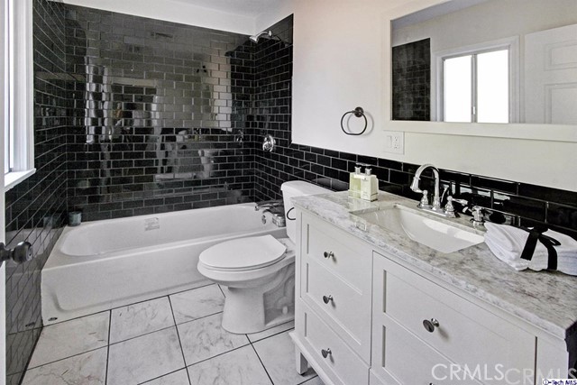 10563 Irma Avenue Tujunga, CA 91042 - Photo 13 of 25 a bathroom with a granite countertop sink a toilet a mirror and bathtub