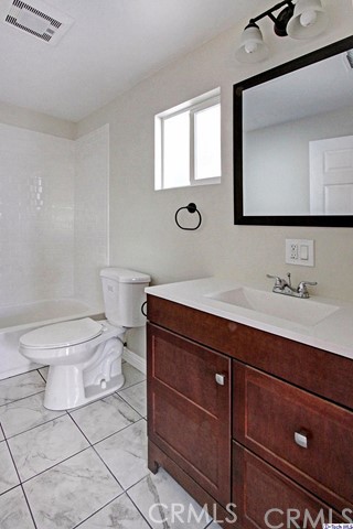 10563 Irma Avenue Tujunga, CA 91042 - Photo 22 of 25 a bathroom with a toilet a sink a mirror and a window