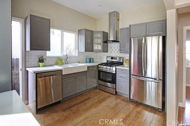 10563 Irma Avenue Tujunga, CA 91042 - Photo 8 of 25 a kitchen with a refrigerator stove and wooden floor
