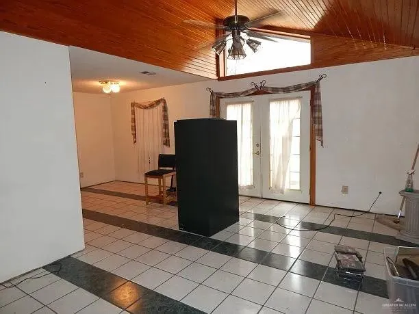 a view of a refrigerator in kitchen and an empty room with wooden floor