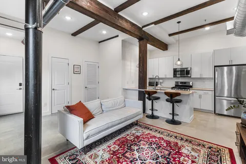 a living room with stainless steel appliances furniture and a rug