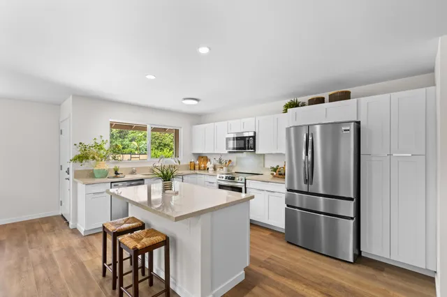 a kitchen with a refrigerator a stove a sink and a dining table with wooden floor