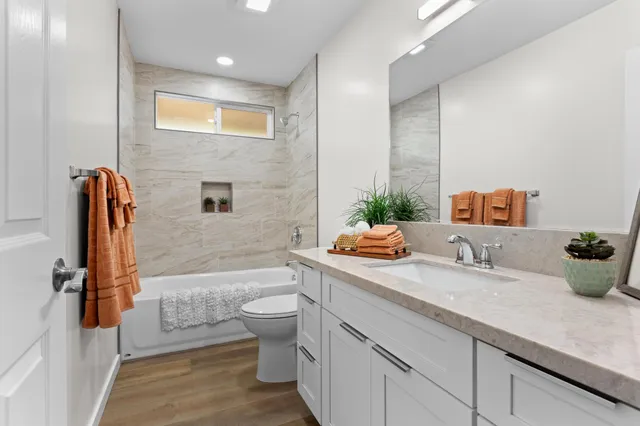 a bathroom with a granite countertop sink a toilet a mirror and bathtub