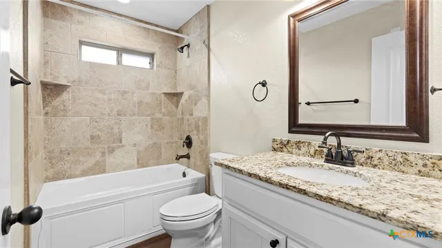 a bathroom with a granite countertop toilet a sink and a bathtub