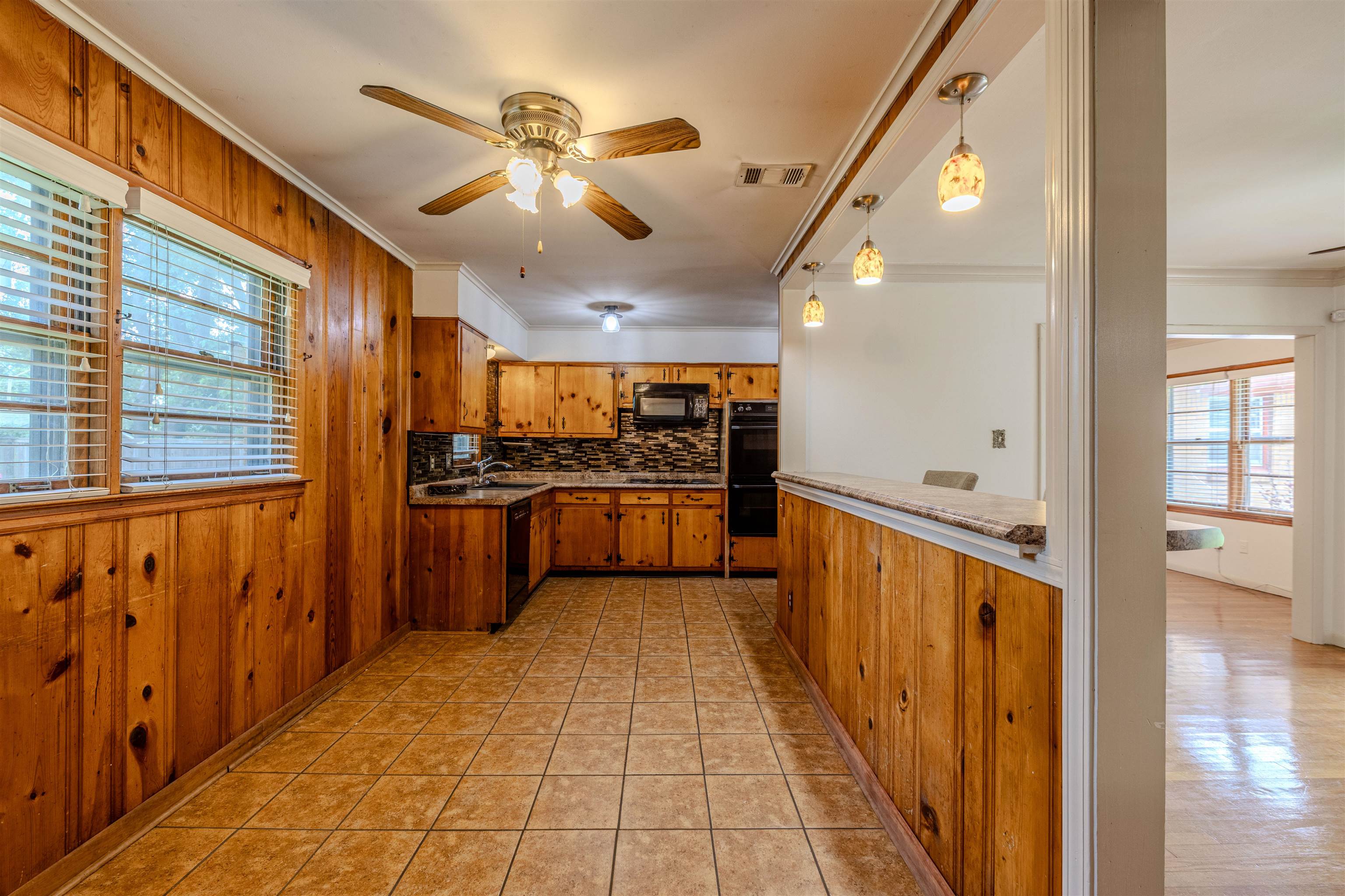 3953 Comanche Road Memphis, TN 38118 - Photo 11 of 24 Kitchen with healthy amount of natural light, crown molding, brown cabinets, ceiling fan, and tasteful backsplash