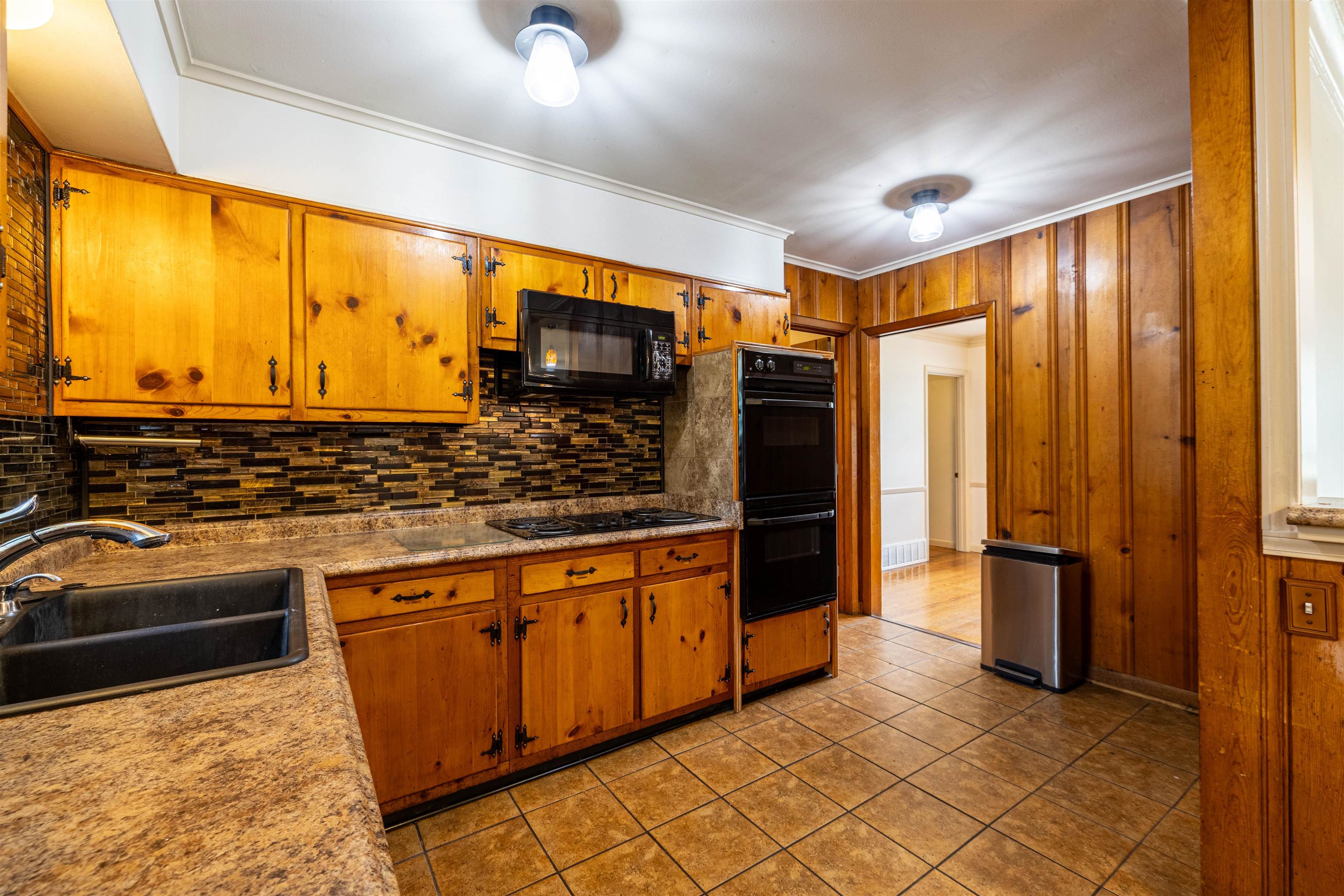 3953 Comanche Road Memphis, TN 38118 - Photo 13 of 24 Kitchen with black appliances, backsplash, brown cabinetry, light tile patterned floors, and ornamental molding