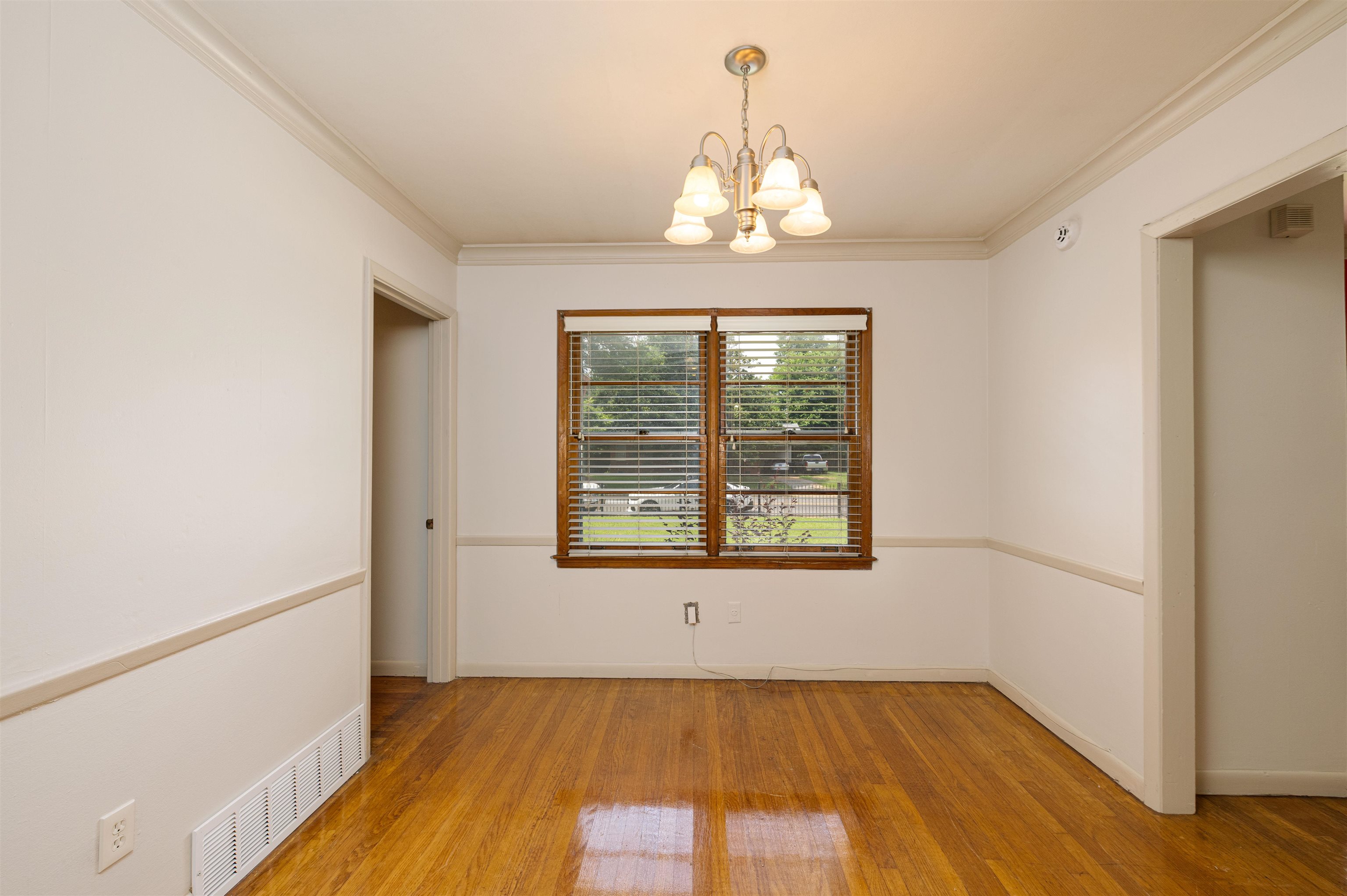 3953 Comanche Road Memphis, TN 38118 - Photo 14 of 24 Empty room featuring a chandelier, crown molding, and wood finished floors