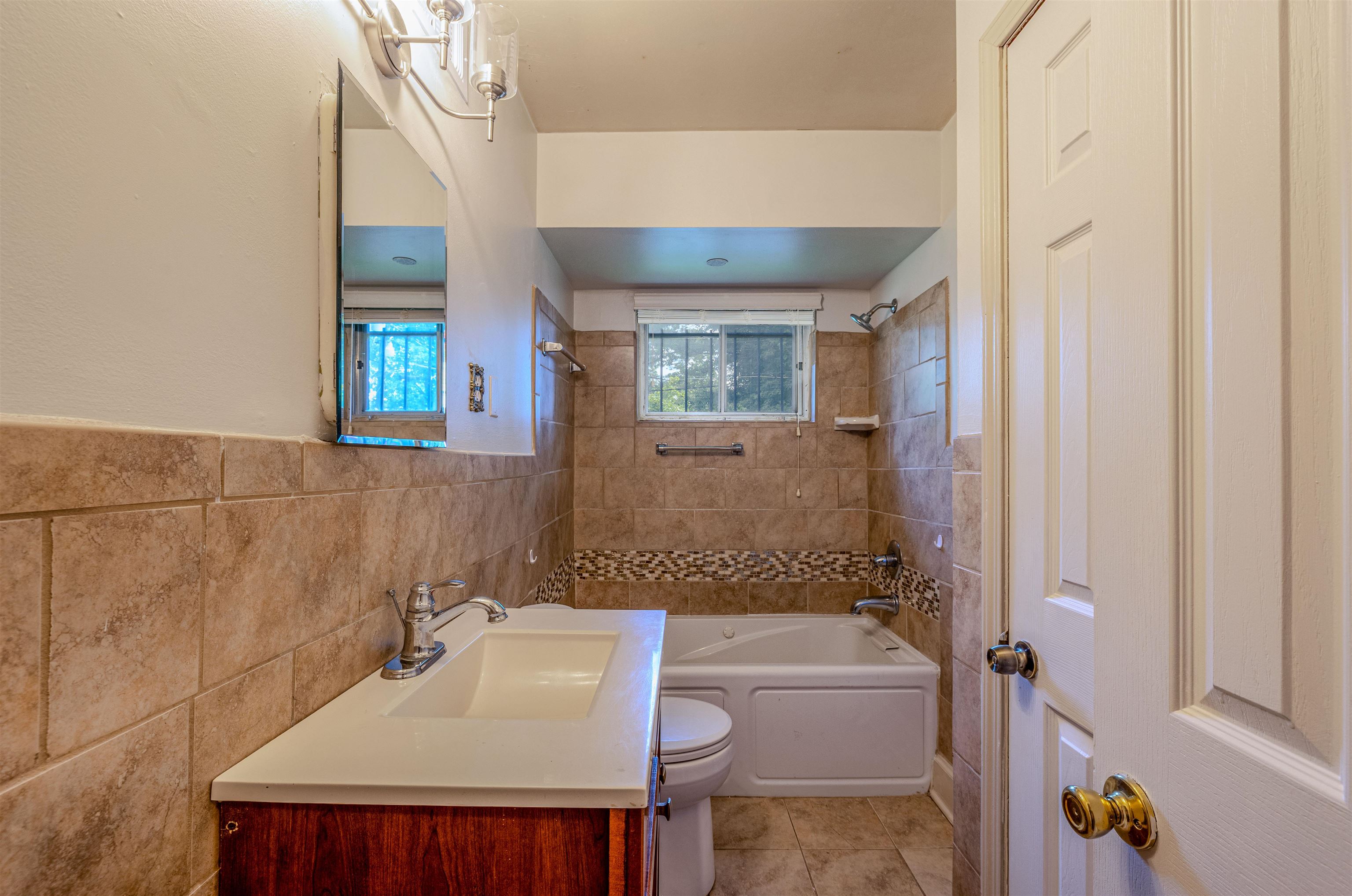 3953 Comanche Road Memphis, TN 38118 - Photo 15 of 24 Bathroom with shower / tub combination, tile walls, vanity, tile patterned flooring, and wainscoting