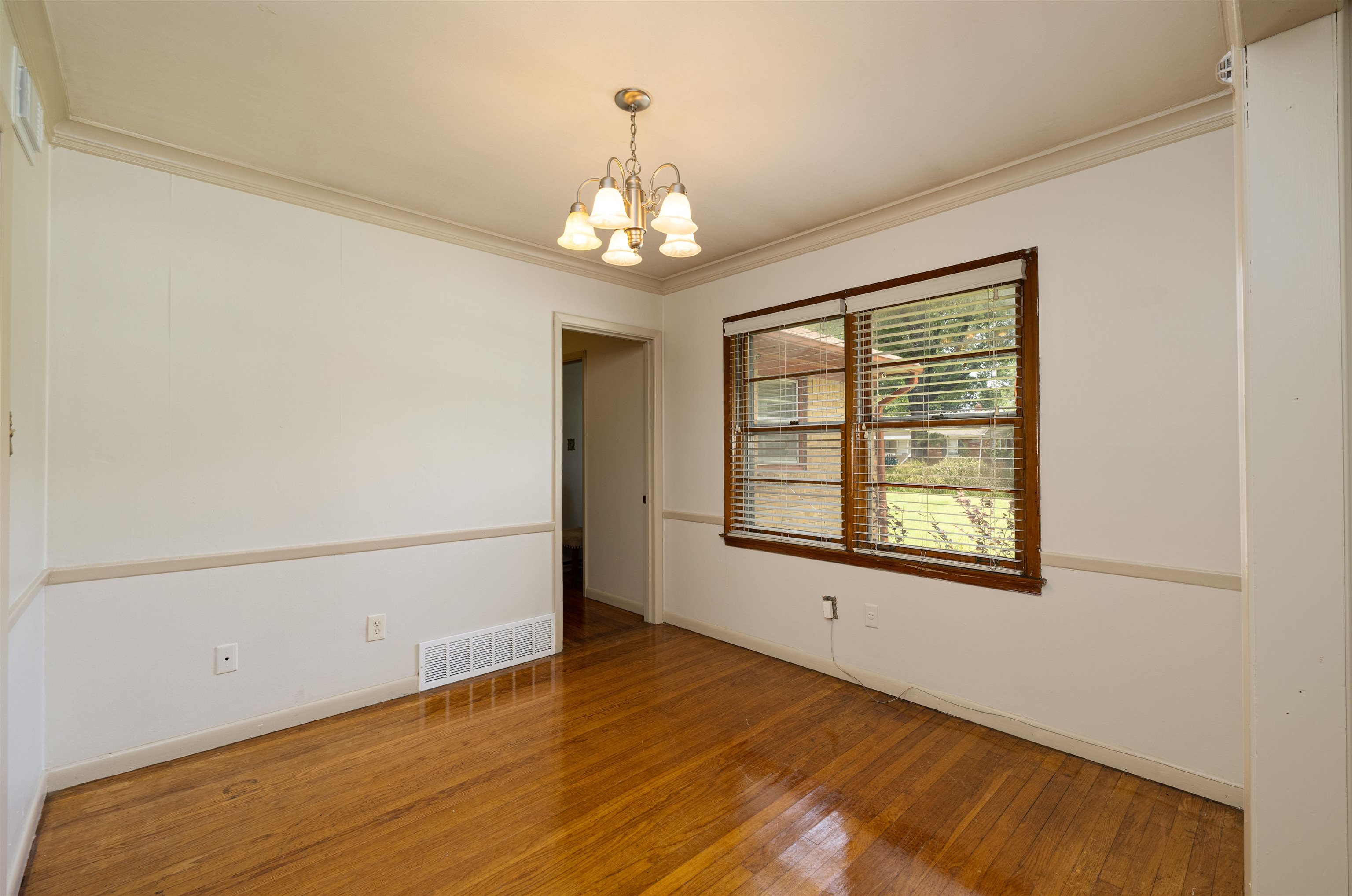 3953 Comanche Road Memphis, TN 38118 - Photo 8 of 24 Empty room with a chandelier, hardwood / wood-style floors, and crown molding