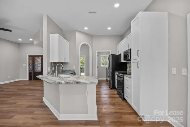 a large kitchen with stainless steel appliances granite countertop a lot of counter space and a sink