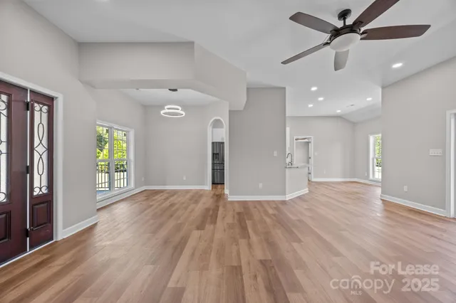 a view of an empty room with window and wooden floor