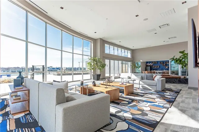 a living room with furniture large windows and wooden floor