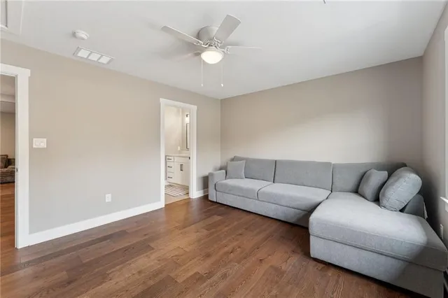a living room with couches and a ceiling fan with wooden floor