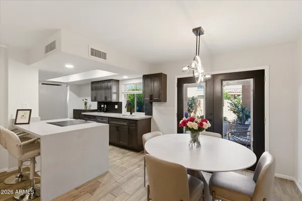 a kitchen with stainless steel appliances kitchen island granite countertop a sink a dishwasher a dining table and chairs with wooden floor