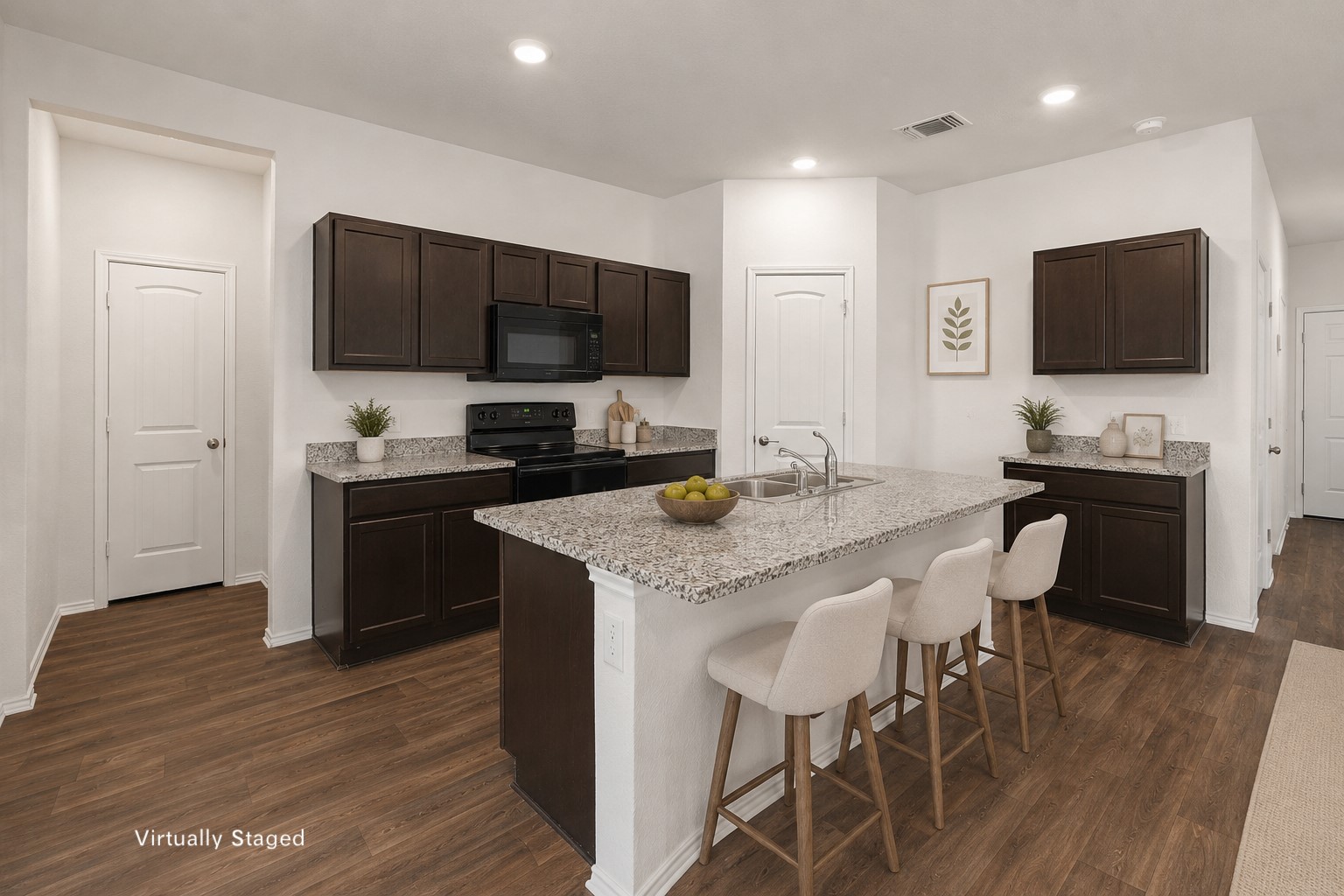 14917 Bajada Rd Manor Manor, TX 78653 - Photo 10 of 31 Kitchen featuring a central island with a double sink, dark wood-finish cabinetry, black appliances including a range and microwave, light-toned granite-style countertops, and wood-finish flooring