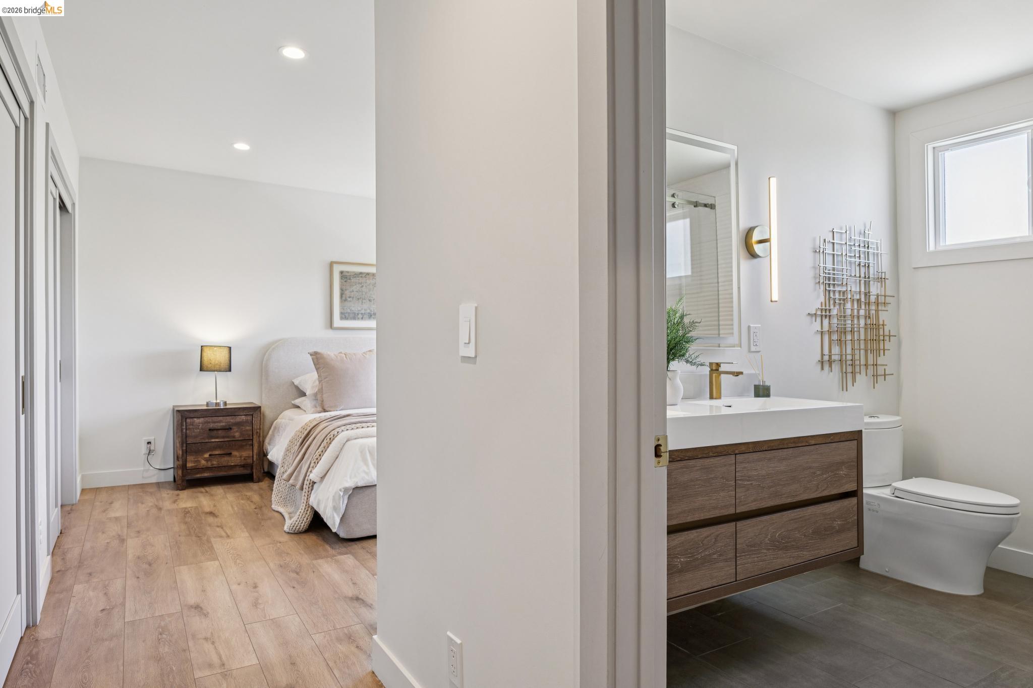 11 Belinda Court San Ramon, CA 94583 - Photo 20 of 33 Contemporary bathroom featuring a floating wood-finish vanity with an integrated sink, gold-finish wall-mounted faucet, and a rectangular mirror with integrated vertical lighting