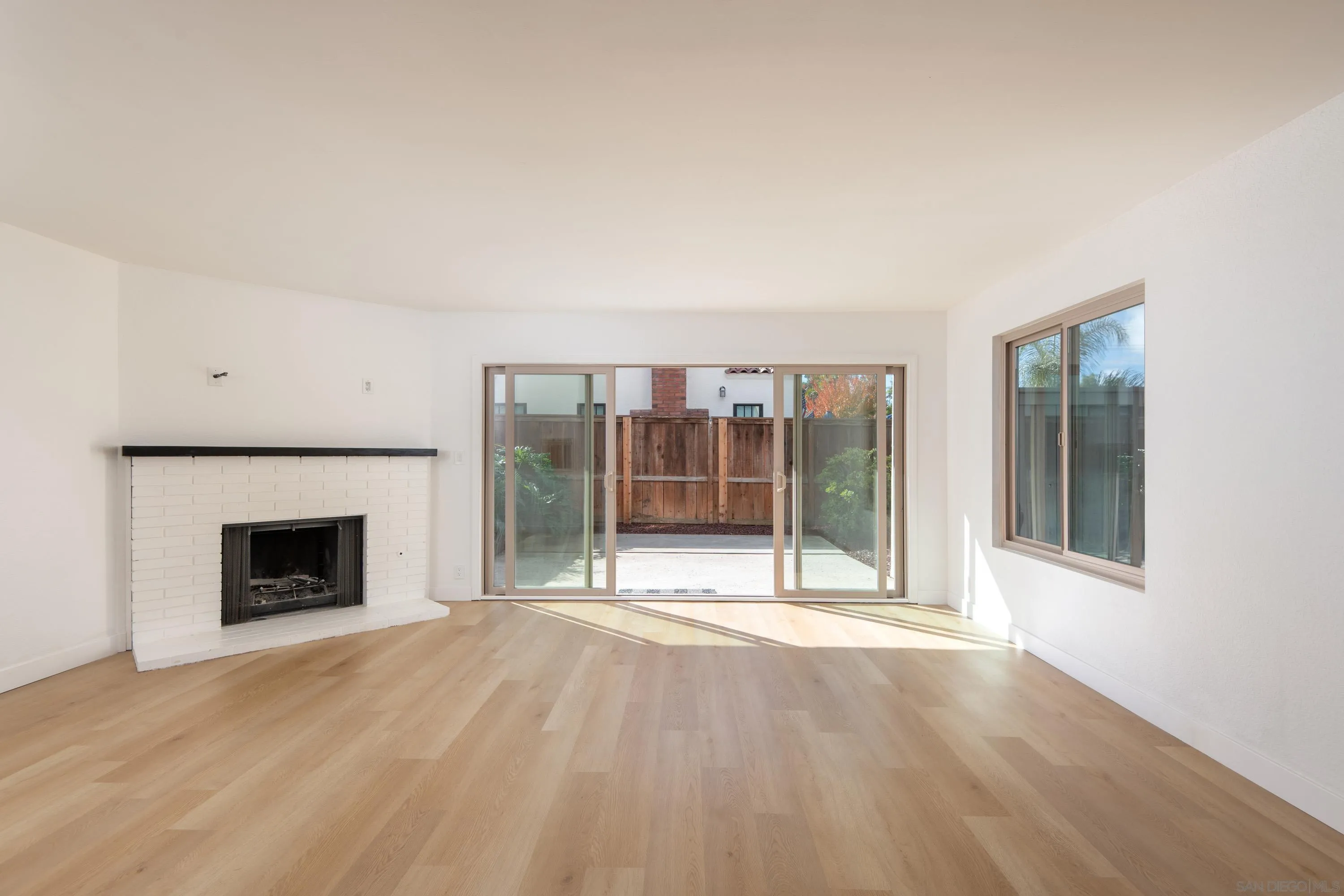 441 D Avenue Coronado, CA 92118 - Photo 14 of 24 an empty room with wooden floor fireplace and windows
