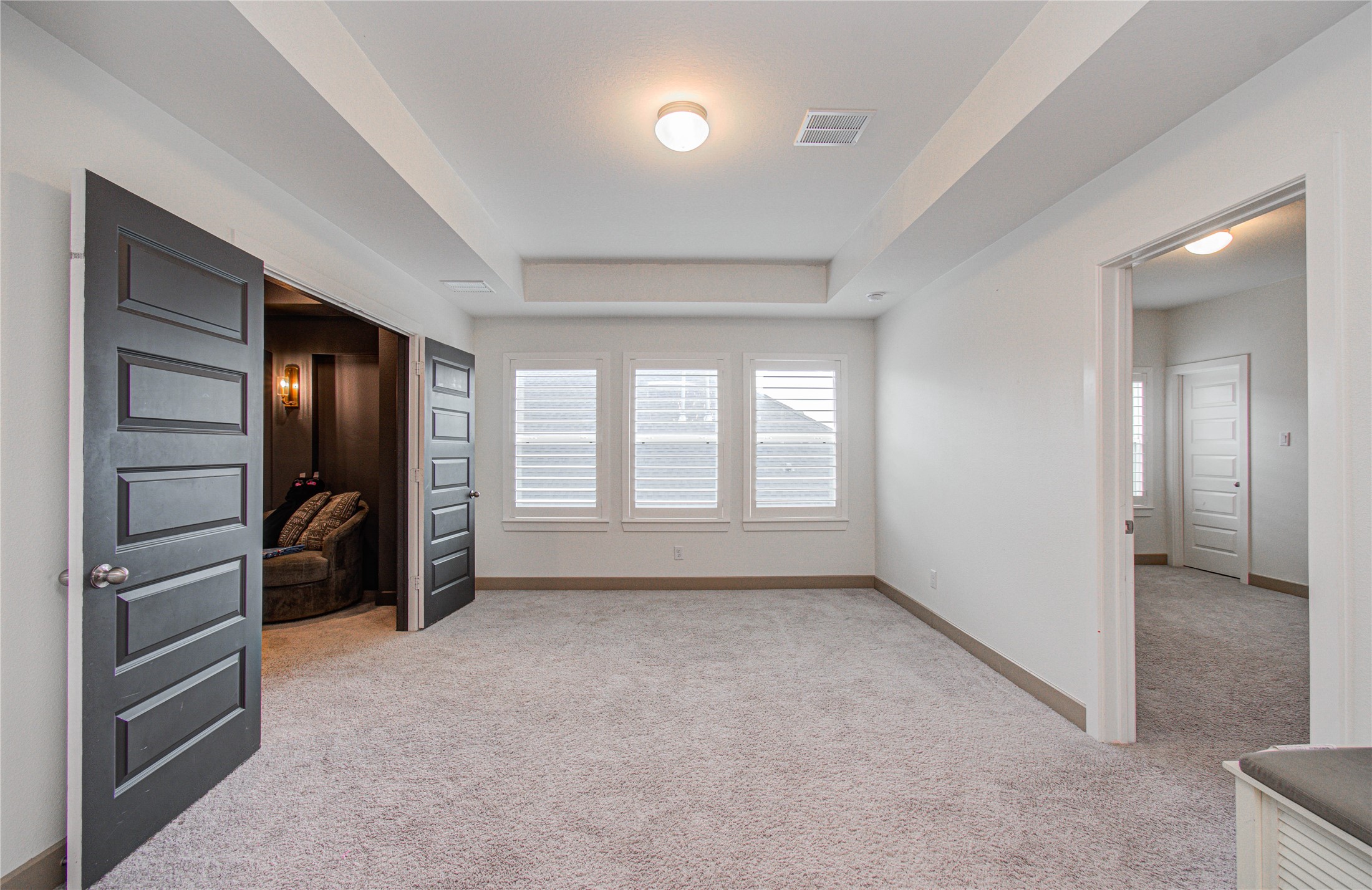 4211 Limestone Terrace Manvel, TX 77578 - Photo 20 of 33 This spacious room features soft carpet, neutral walls, and ample natural light from three large windows. It has two doorways, one leading to another room and one to a cozy theater space with plush seating. Ideal for relaxation and entertainment.