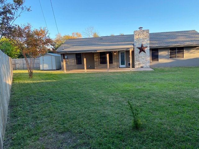 1002 Creekbend Cove Pflugerville, TX 78660 - Photo 5 of 16 Back of property featuring a chimney, a storage shed, and a shingled roof
