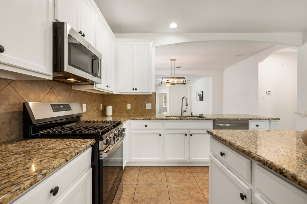 11744 Easy Street Austin, TX 78748 - Photo 20 of 40 Gleaming granite countertops pair beautifully with white cabinetry and a tiled backsplash.