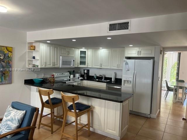 425 Grapetree Drive, Unit 209 Key Biscayne, FL 33149 - Photo 3 of 6 a kitchen with stainless steel appliances granite countertop a table chairs sink and cabinets